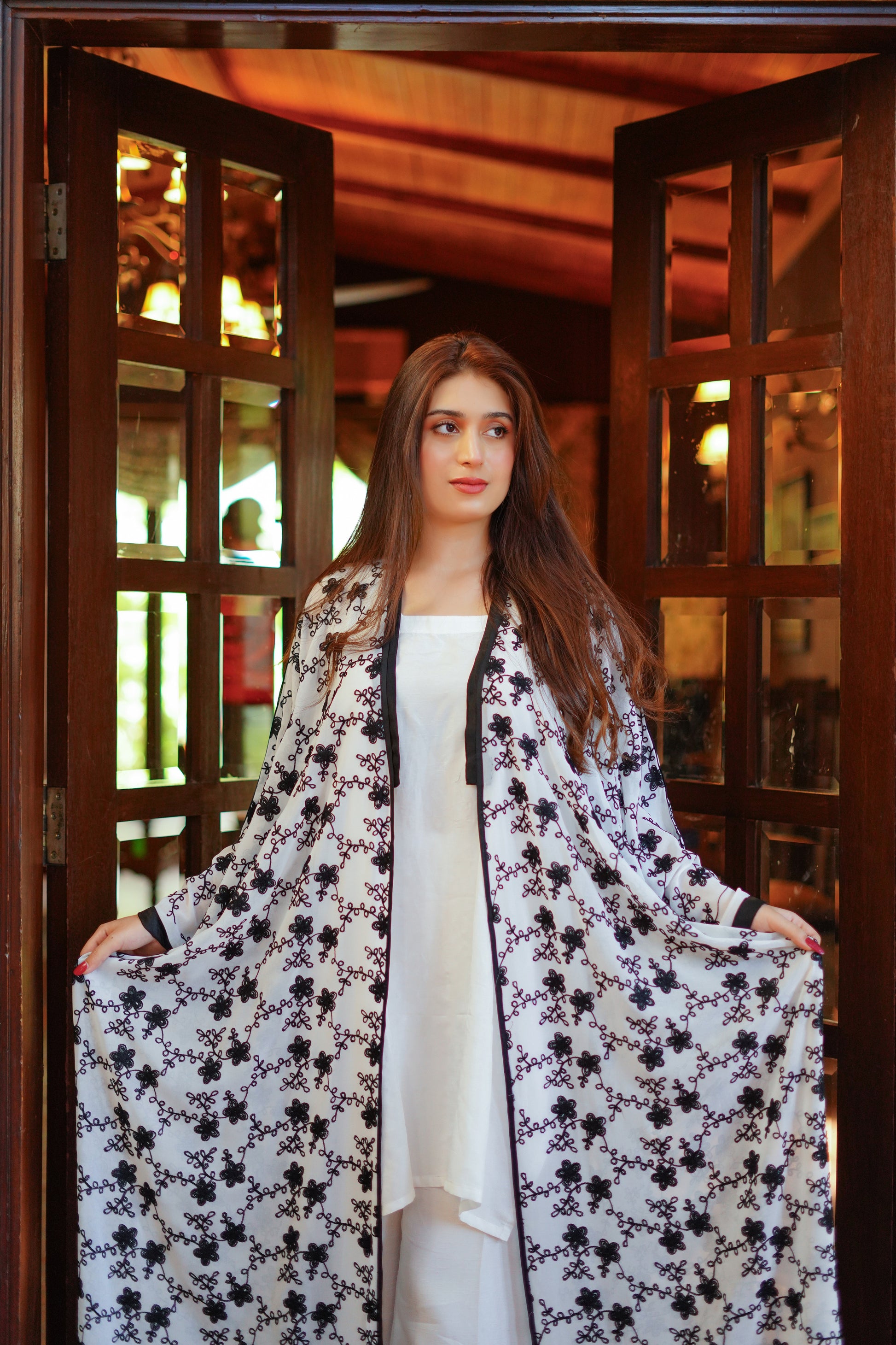 Stylish black and white printed kimono-style long coat for women – paired with a white inner dress and pants. Perfect for modern, modest, and elegant looks. Shop trendy women's clothing online.