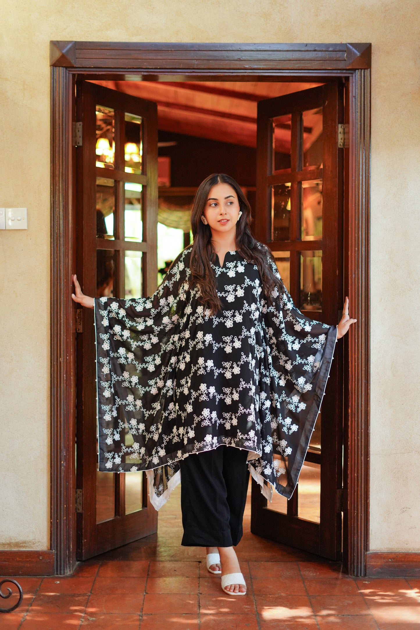 Elegant black and white printed cape-style tunic for women – paired with black pants and white heels. Ideal for modern, modest, and chic looks. Shop stylish women's outfits online.